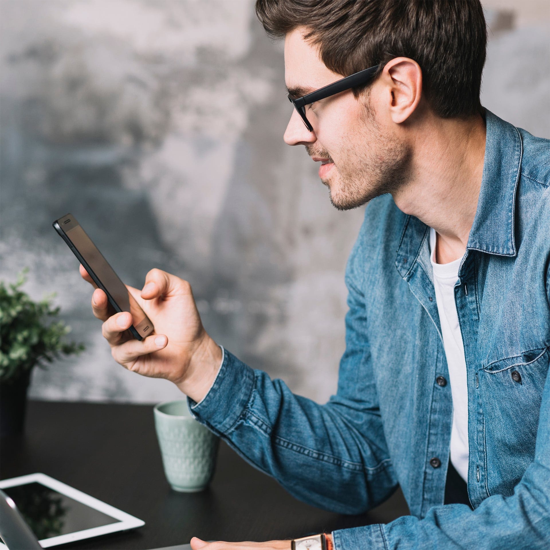 Primo piano laterale di un ragazzo mentre utilizza il proprio smartphone