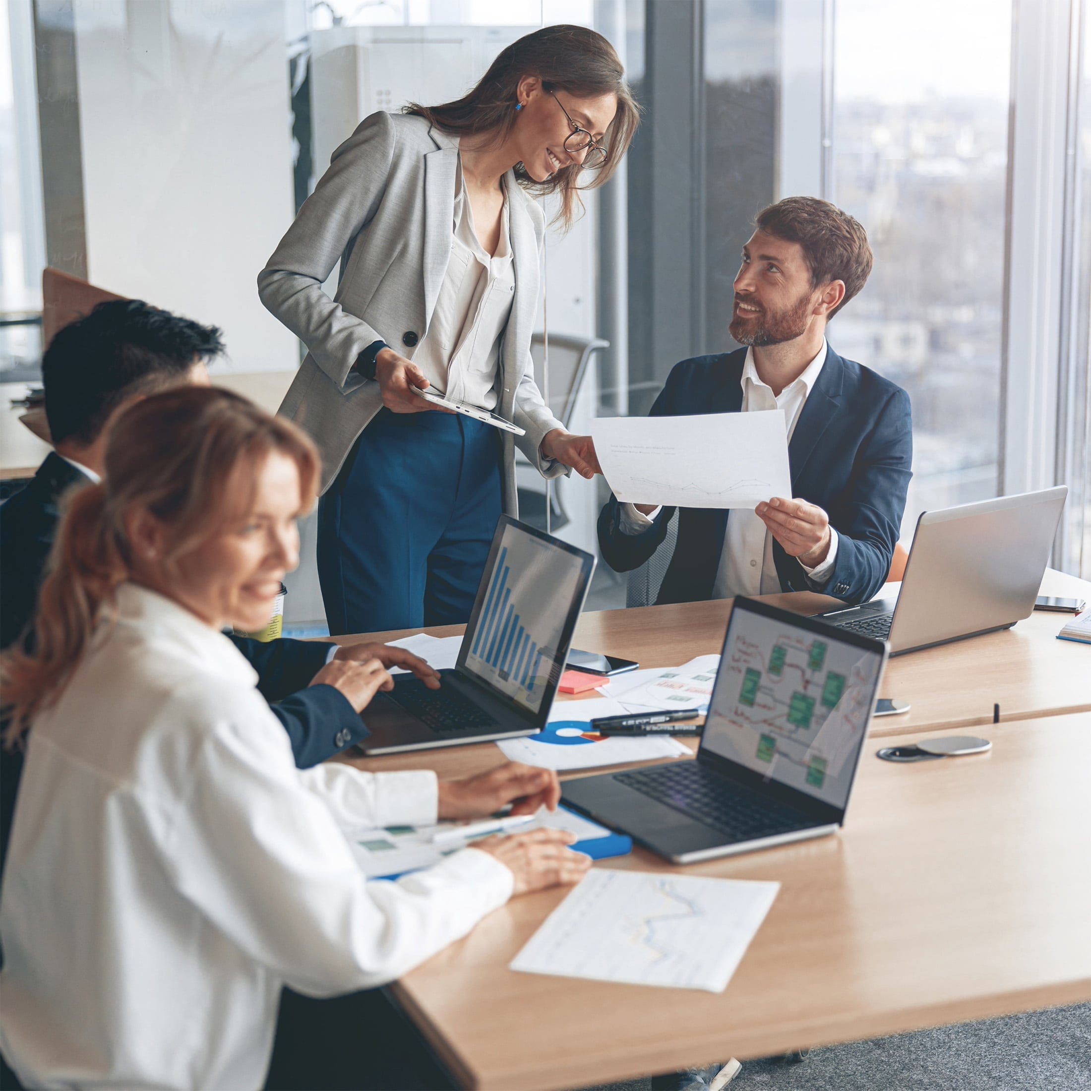 Quattro persone sedute a un tavolo discutono mentre analizzano dei documenti