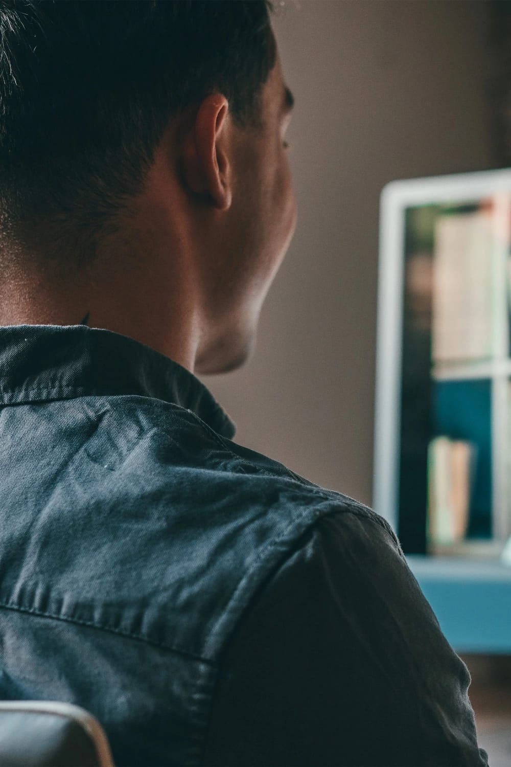Scatto da dietro, altezza spalle, di un ragazzo in video call con una collega