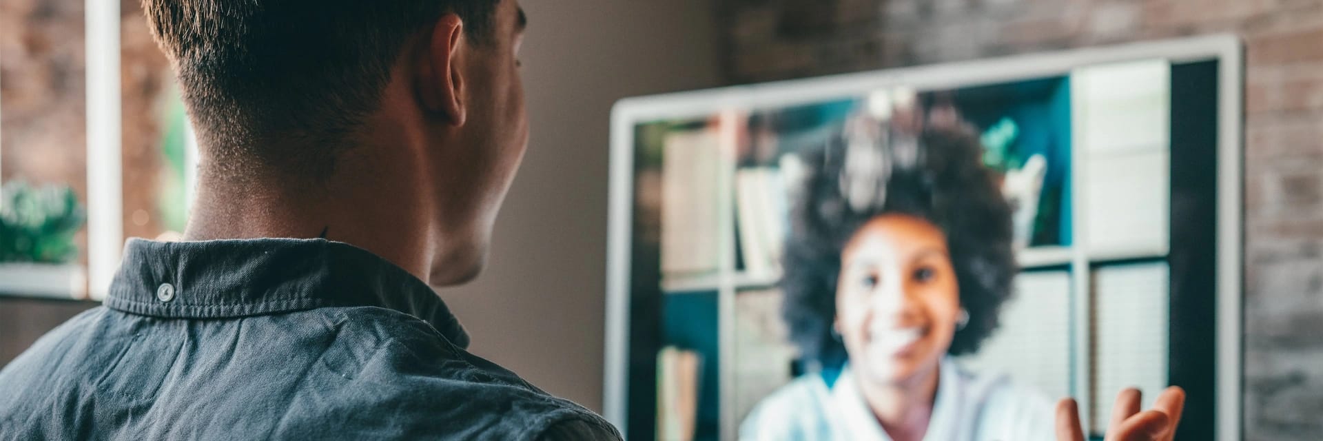 Scatto da dietro, altezza spalle, di un ragazzo in video call con una collega