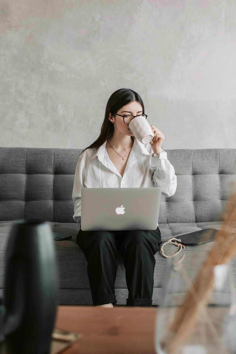 Una ragazza seduta sul suo divano di casa con il suo laptop sulle ginocchia